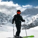 pexels-photo-2405649-2405649 Energetic skier in black gear enjoying snowy slopes under blue sky and sunlight.